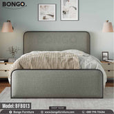 A full size bed with a gray headboard and footboard, featuring a white mattress, placed in a room with nightstands and wall art.